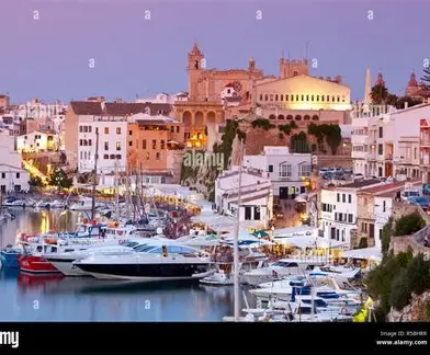 Ciutadella harbour at dusk with the cathedral silhouette above fishing boats and yachts along the historic quay
